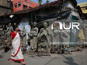 A woman speaks on her mobile phone as she walks past semi-finished clay idols of the Hindu mythological characters ''Dakinis'' and ''Yoginis...