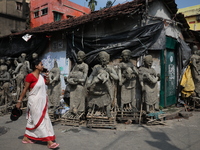 A woman speaks on her mobile phone as she walks past semi-finished clay idols of the Hindu mythological characters ''Dakinis'' and ''Yoginis...