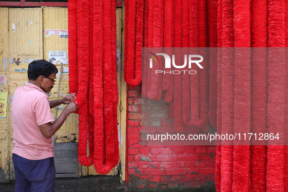 A vendor prepares the garlands kept on sale to decorate the idol of the Hindu goddess Kali at a workshop area in Kolkata, India, on October...