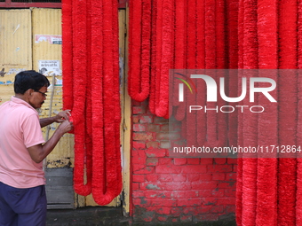 A vendor prepares the garlands kept on sale to decorate the idol of the Hindu goddess Kali at a workshop area in Kolkata, India, on October...