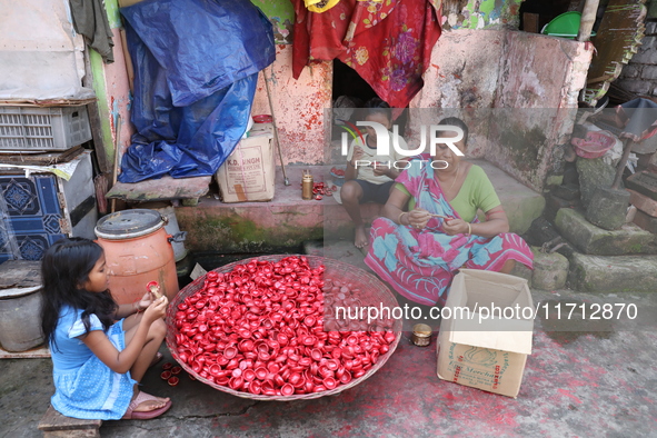 A woman and girls color earthen lamps, which are used to decorate temples and homes during the Hindu festival of Diwali, in Kolkata, India,...