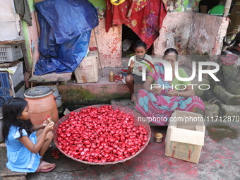 A woman and girls color earthen lamps, which are used to decorate temples and homes during the Hindu festival of Diwali, in Kolkata, India,...