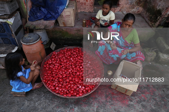 A woman and girls color earthen lamps, which are used to decorate temples and homes during the Hindu festival of Diwali, in Kolkata, India,...