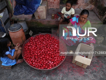 A woman and girls color earthen lamps, which are used to decorate temples and homes during the Hindu festival of Diwali, in Kolkata, India,...