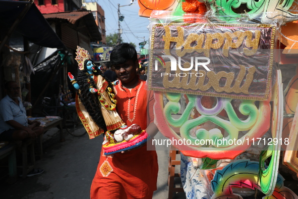 A man carries an idol of the Hindu goddess Kali for worship and walks towards his house in a workshop area ahead of the Diwali festival in K...