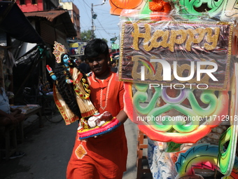 A man carries an idol of the Hindu goddess Kali for worship and walks towards his house in a workshop area ahead of the Diwali festival in K...