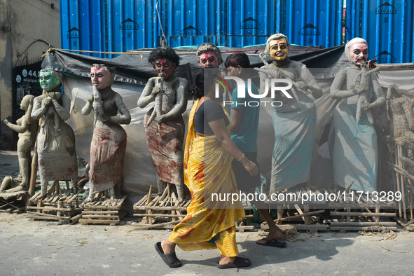 People walk past semi-finished clay idols of the Hindu mythological characters 'Dakinis' and 'Yoginis', who are worshipped along with the Hi...