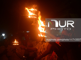 Priests, along with residents of Siliguri, illuminate earthen lamps on the riverbank of the Mahananda in Siliguri, India, on October 27, 202...