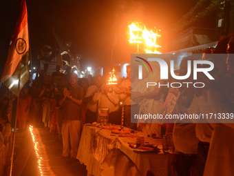 Priests, along with residents of Siliguri, illuminate earthen lamps on the riverbank of the Mahananda in Siliguri, India, on October 27, 202...