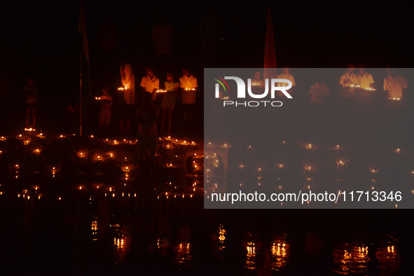 Priests, along with residents of Siliguri, illuminate earthen lamps on the riverbank of the Mahananda in Siliguri, India, on October 27, 202...