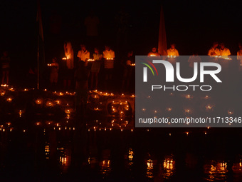 Priests, along with residents of Siliguri, illuminate earthen lamps on the riverbank of the Mahananda in Siliguri, India, on October 27, 202...