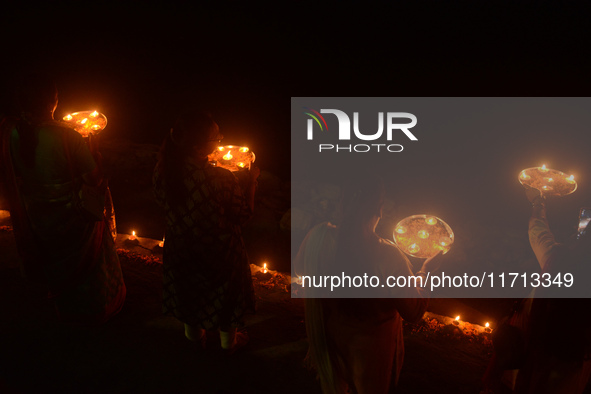 Priests, along with residents of Siliguri, illuminate earthen lamps on the riverbank of the Mahananda in Siliguri, India, on October 27, 202...