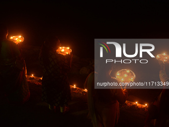 Priests, along with residents of Siliguri, illuminate earthen lamps on the riverbank of the Mahananda in Siliguri, India, on October 27, 202...