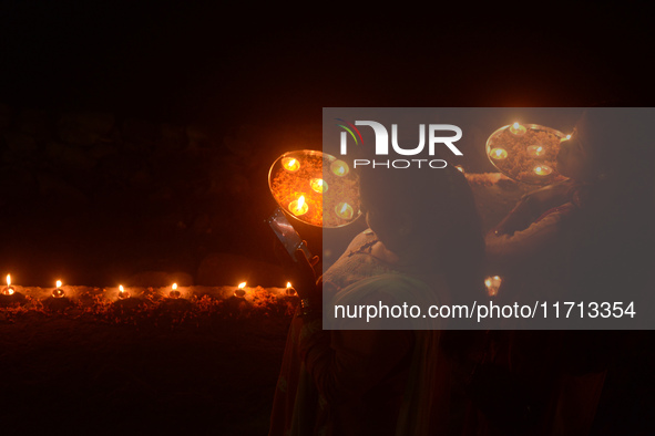 Priests, along with residents of Siliguri, illuminate earthen lamps on the riverbank of the Mahananda in Siliguri, India, on October 27, 202...