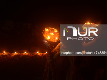 Priests, along with residents of Siliguri, illuminate earthen lamps on the riverbank of the Mahananda in Siliguri, India, on October 27, 202...