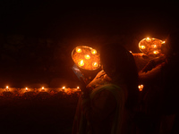 Priests, along with residents of Siliguri, illuminate earthen lamps on the riverbank of the Mahananda in Siliguri, India, on October 27, 202...