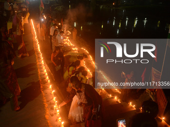 Priests, along with residents of Siliguri, illuminate earthen lamps on the riverbank of the Mahananda in Siliguri, India, on October 27, 202...