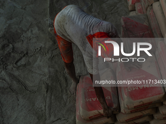 Porters load sacks of cement at the port of Belawan for the USU Residence III housing complex in Patumbak, Deli Serdang, North Sumatra, on O...