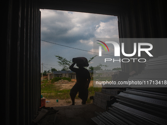 Porters load sacks of cement at the port of Belawan for the USU Residence III housing complex in Patumbak, Deli Serdang, North Sumatra, on O...