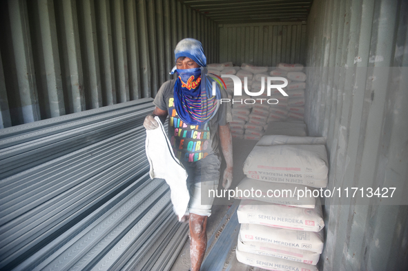 Porters load sacks of cement at the port of Belawan for the USU Residence III housing complex in Patumbak, Deli Serdang, North Sumatra, on O...