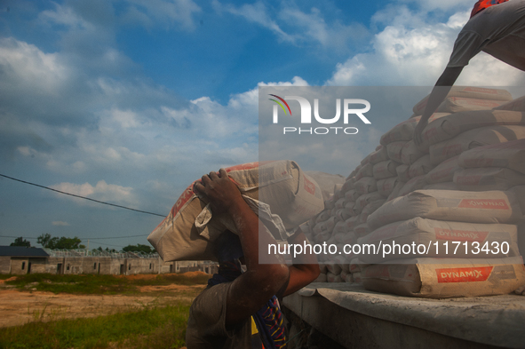 Porters load sacks of cement at the port of Belawan for the USU Residence III housing complex in Patumbak, Deli Serdang, North Sumatra, on O...