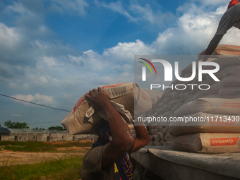 Porters load sacks of cement at the port of Belawan for the USU Residence III housing complex in Patumbak, Deli Serdang, North Sumatra, on O...