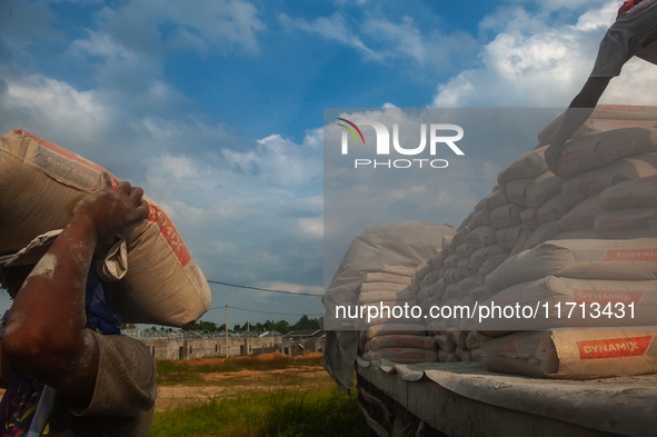 Porters load sacks of cement at the port of Belawan for the USU Residence III housing complex in Patumbak, Deli Serdang, North Sumatra, on O...