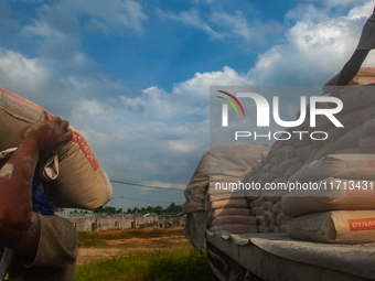 Porters load sacks of cement at the port of Belawan for the USU Residence III housing complex in Patumbak, Deli Serdang, North Sumatra, on O...