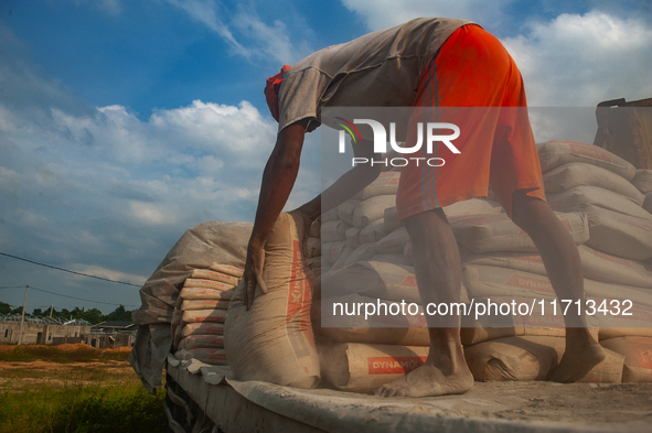 Porters load sacks of cement at the port of Belawan for the USU Residence III housing complex in Patumbak, Deli Serdang, North Sumatra, on O...