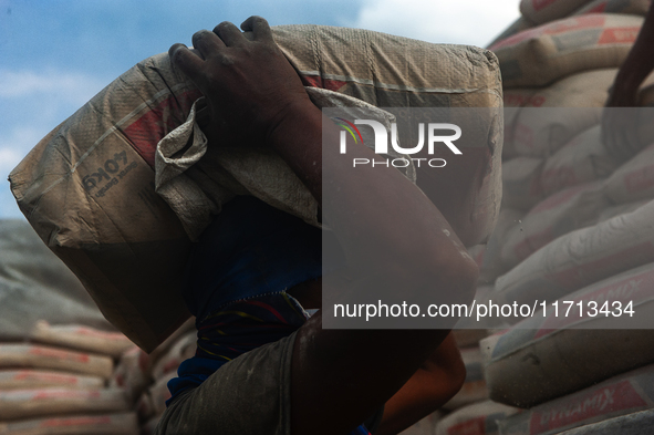 Porters load sacks of cement at the port of Belawan for the USU Residence III housing complex in Patumbak, Deli Serdang, North Sumatra, on O...