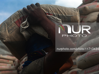 Porters load sacks of cement at the port of Belawan for the USU Residence III housing complex in Patumbak, Deli Serdang, North Sumatra, on O...