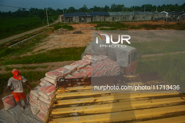 Porters load sacks of cement at the port of Belawan for the USU Residence III housing complex in Patumbak, Deli Serdang, North Sumatra, on O...