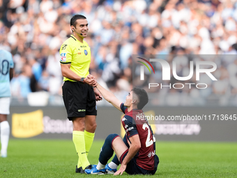 Referee Marco Piccinini helps Johan Vasquez of Genoa CFC get up during the Serie A Enilive match between SS Lazio and Genoa CF at Stadio Oli...