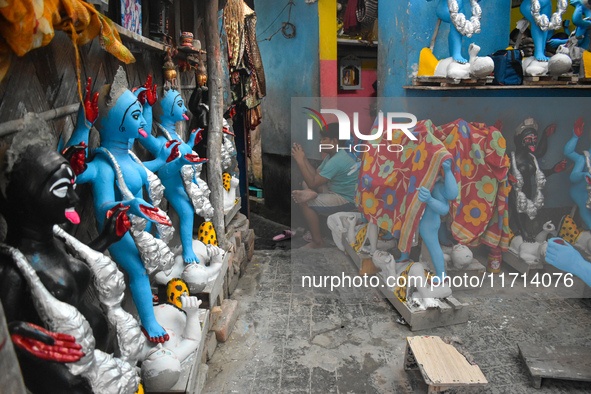 A boy sits outside his home checking his mobile inside a pottery hub in Kolkata, India, on October 27, 2024. 