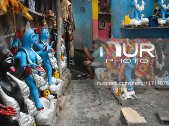 A boy sits outside his home checking his mobile inside a pottery hub in Kolkata, India, on October 27, 2024. (