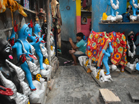 A boy sits outside his home checking his mobile inside a pottery hub in Kolkata, India, on October 27, 2024. (