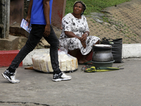 An official with a sensitization leaflet walks past a street food vendor as the Federal Nigeria Society for the Blind organizes a walk and c...