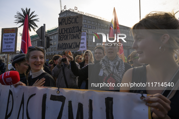 People hold signs and shout slogans as they rally against the Polish Prime Minister Donald Tusk's decision to suspend the right to asylum wi...