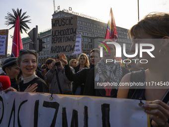 People hold signs and shout slogans as they rally against the Polish Prime Minister Donald Tusk's decision to suspend the right to asylum wi...