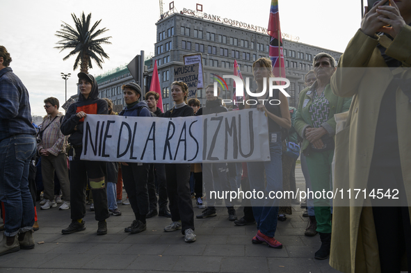 People hold a banner that reads ''No to racism'' as they rally against the Polish Prime Minister Donald Tusk's decision to suspend the right...