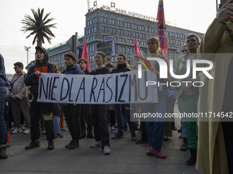 People hold a banner that reads ''No to racism'' as they rally against the Polish Prime Minister Donald Tusk's decision to suspend the right...