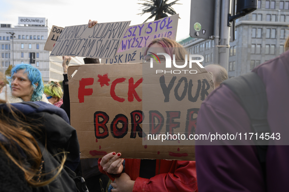 People hold signs and shout slogans as they rally against the Polish Prime Minister Donald Tusk's decision to suspend the right to asylum wi...