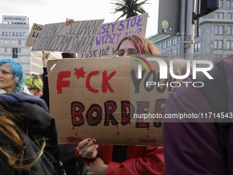 People hold signs and shout slogans as they rally against the Polish Prime Minister Donald Tusk's decision to suspend the right to asylum wi...