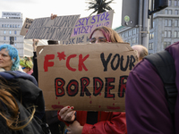 People hold signs and shout slogans as they rally against the Polish Prime Minister Donald Tusk's decision to suspend the right to asylum wi...