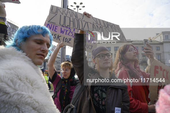 Demonstrators hold a sign that reads ''Ukrainians in solidarity with world's refugees'' and shout slogans as they rally against the Polish P...