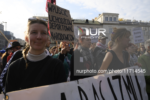 People hold signs that read ''Let in migrants, deport nationalists'' and shout slogans as they rally against the Polish Prime Minister Donal...