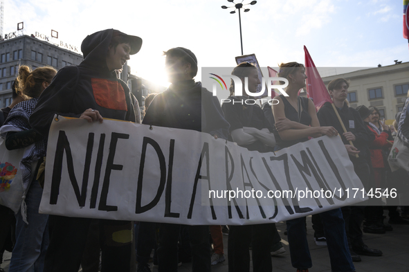 People hold a banner that reads ''No to racism'' as they rally against the Polish Prime Minister Donald Tusk's decision to suspend the right...