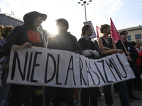 People hold a banner that reads ''No to racism'' as they rally against the Polish Prime Minister Donald Tusk's decision to suspend the right...