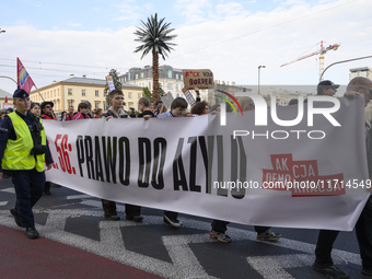 People carry a banner that reads ''Article 56: Right to asylum'' as they rally against the Polish Prime Minister Donald Tusk's decision to s...