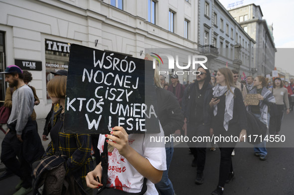 A demonstrator holds a sign that reads ''Amongst night's silence someone is dying in the woods'' as she rallies against the Polish Prime Min...